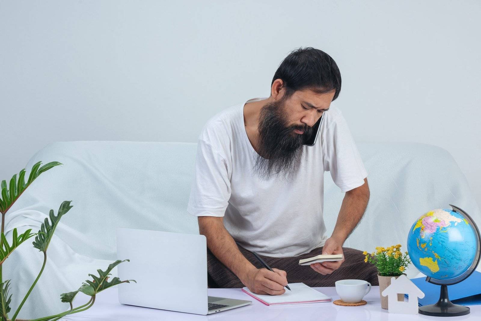 Old man is working while using laptop on sofa at home.